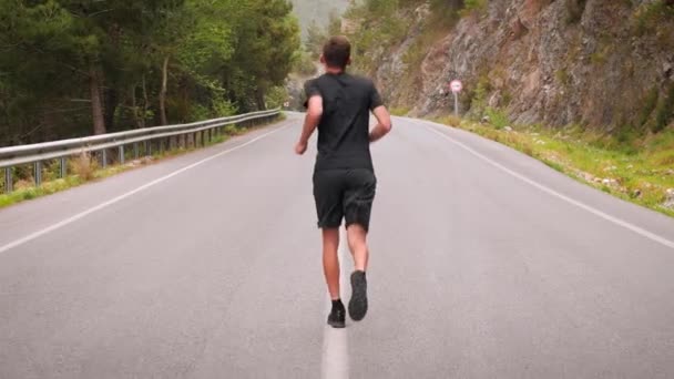 Concepto de funcionamiento. Corredor masculino entrenando al aire libre, haciendo ejercicio en carretera de montaña — Vídeo de stock