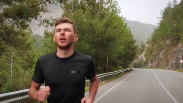 Triatleta muscular atlético correndo na estrada da montanha. Homem esportivo corre ao ar livre — Vídeo de Stock
