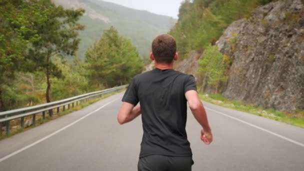 ランニングとジョギングのコンセプト。空の山道を走る若いスポーツマン — ストック動画