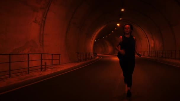 Kvinnlig löpare i tunneln. Kvinnan som springer längs en tom tunnel. Idrottsbegreppet — Stockvideo