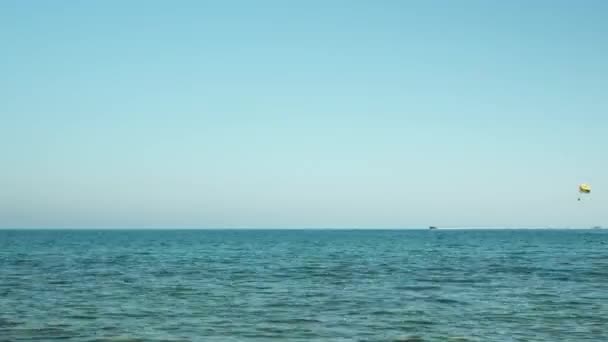 Yellow parachute flying over sea water surface. Sea parasailing across seaside — Vídeos de Stock