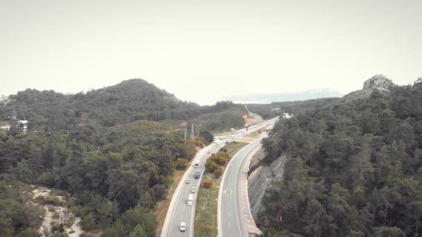 Nowoczesna autostrada otoczona górami. Samochody poruszające się szybko na autostradzie prędkości — Wideo stockowe