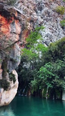 Etrafı kayalık tepelerle çevrili berrak sularla çevrili bir dağ gölü. Dikey video