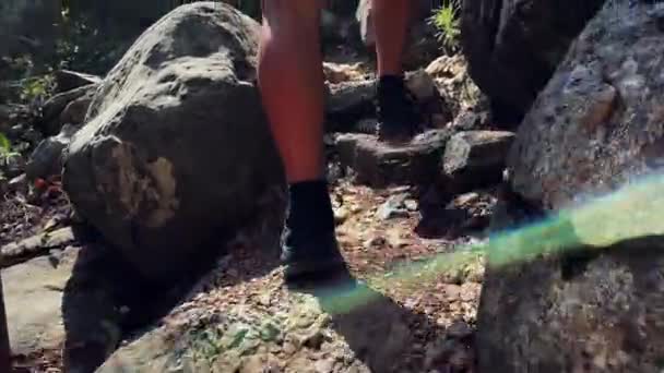 Woman in hiking sneakers walking up to mountain peak through huge stones — ストック動画