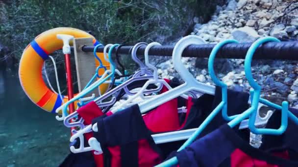 Vestes de protection rouges pour la randonnée en rafting suspendues à l'extérieur près du lac ou de la rivière — Video
