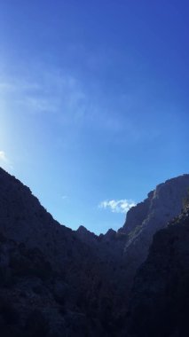 Ufukta dağ zirveleri olan açık mavi gökyüzünün zamanı. Güzel bulutlar