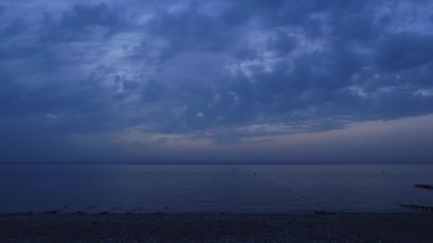 Ruhige ruhige Meerwasseroberfläche in der Dämmerung gegen bewölkten Himmel. Sonnenaufgang über dem Meer — Stockvideo
