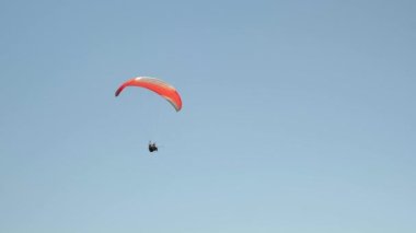 Açık mavi gökyüzüne karşı uçan kırmızı paraşüt. Ekstrem sporlar paragliding