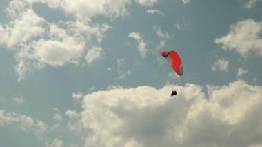 Paraglider arka planda kırmızı paraşütle uçuyor ve güzel bulutlar