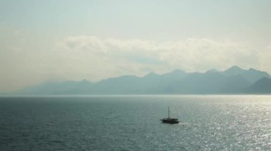 Güneşli bir günde gölde yüzen balıkçı teknesi. Göl yüzeyinde küçük bir gemi hareket ediyor.