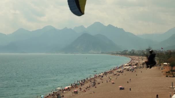 Man with parachute flying over sandy beach. Paragliding. Summer recreation — Wideo stockowe