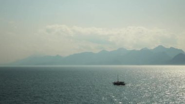 Boat floating in lagoon. Beautiful calm blue sea water with foggy mountains