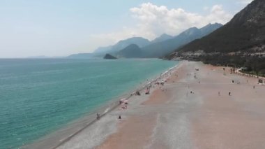 Arkasında dağlar olan geniş kumlu bir sahil. Akdeniz Kıyısı