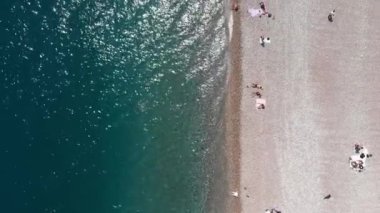 Sahildeki insanlar. Kumsalda şemsiyelerin altında yatan kaygısız insanlar.