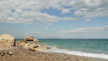 Deniz mavisi dalgalar yüksek kayalıklarda kırılır. Kayalık kıyı şeridinde dalgalar kıvrılır.