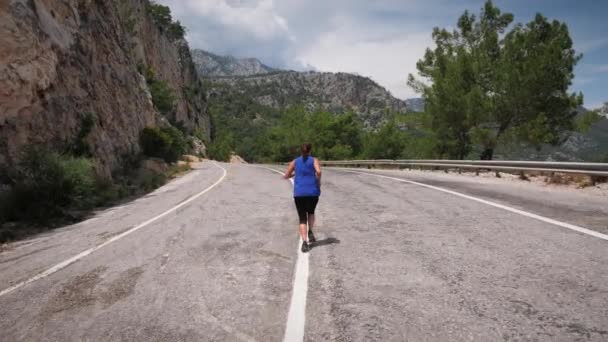 Mujer enérgica corriendo en la carretera de montaña.Actividad de fitness y búsqueda de recreación — Vídeo de stock