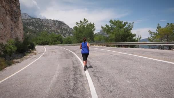 Een vrouw die langs rotsachtige kusten loopt. Gezonde hardloop- en outdooroefeningen — Stockvideo