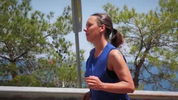 Jeune athlète féminine en tenue de sport courir sur la route à la journée ensoleillée d'été — Video