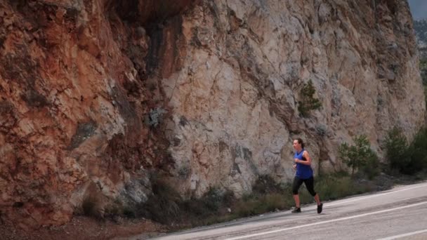 Una mujer corriendo rápido por un acantilado rocoso. Actividad intensa de entrenamiento en ejecución — Vídeo de stock