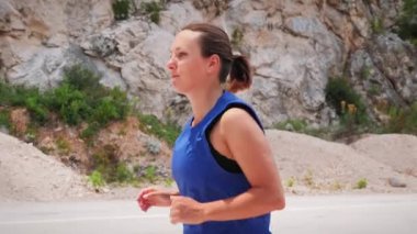 Young motivated woman running in mountains. Active female jogging outdoors