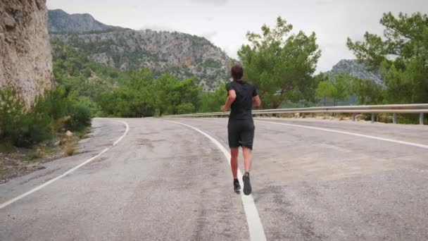 Ajuste jovem bonito correndo na estrada em montanhas.Atleta masculino correndo ao ar livre — Vídeo de Stock