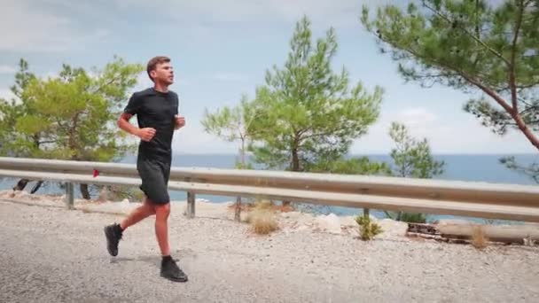 Young active man jogging in nature.Man running outdoors along beautiful seashore — Stock videók