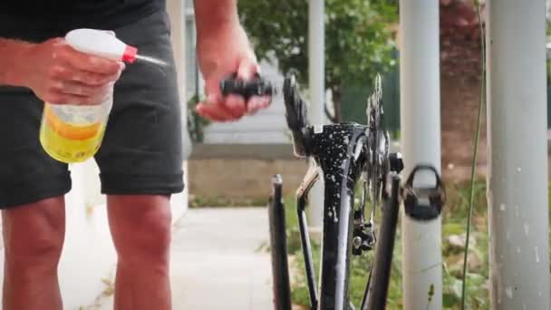 Städning och tvätt av cykel utomhus. Man sprutning avfettare på väg cykel — Stockvideo