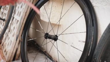 Bisiklet tekerleğini hortumla yıkayan bir adam. Motosiklet tamircisi bisikleti temizliyor