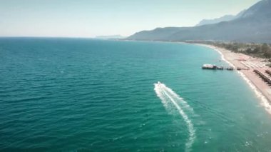 Kumlu sahil kıyısında sürat teknesi. Su yüzeyinde yüzen beyaz bir yat.