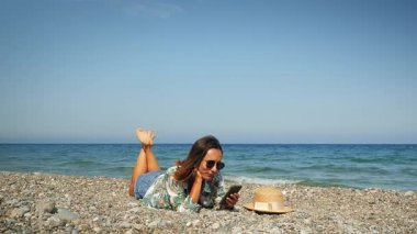 Güneşli bir günde kumsalda dinlenen bir kadın. Sahilde kaygısız gülümseyen bir kadın.