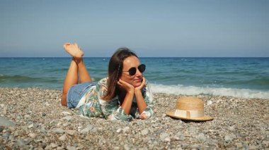 Deniz kenarında bir kadın. Rüzgarlı bir yaz gününde, deniz kıyısında uzanan büyüleyici bir kadın.