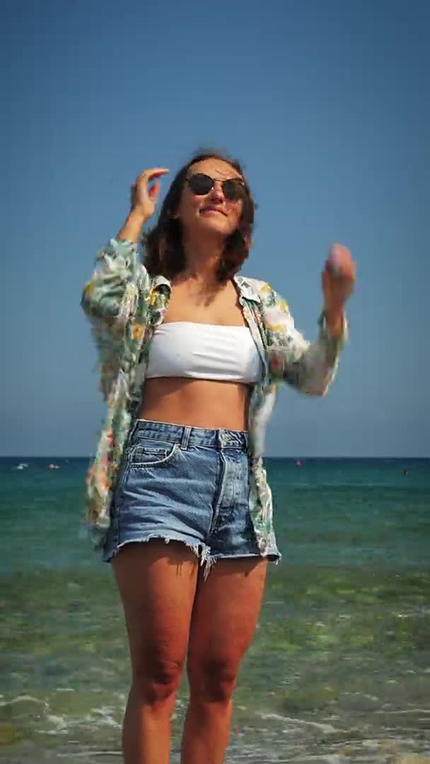 Smiling female standing on seashore at windy day and smiling, vertical video — Stok Video
