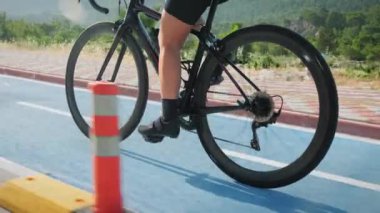 Bisiklet yolunda bisiklet sürmek. Formda kadın bacakları bisiklete pedal çeviriyor, sıkı çalışıyor. Formda bisiklet süren sportif atletizm bisikletçisi bisiklet üzerinde pedal çeviriyor. Fitness kardiyo egzersizleri