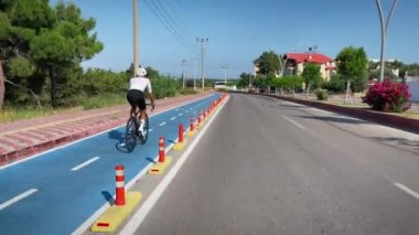 Erkek bisiklet yol bisikleti. Dışarıda bisiklete binen genç bir bisikletçi. Bisiklet kıyafetleri ve beyaz kasklı profesyonel yol bisikletçisi bisiklet yolunda bisiklet sürüyor. Spor motivasyonu. Fitness etkinliği
