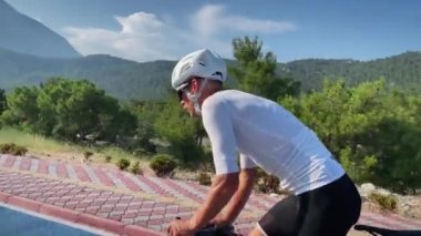 Bisikletli profesyonel erkek bisikletçi eğitiminin portresi. Bisiklet süren bir sporcu, bisikletli bisiklet yolunda yoğun pedal çeviriyor. Spor motivasyon konsepti. Fitness etkinliği