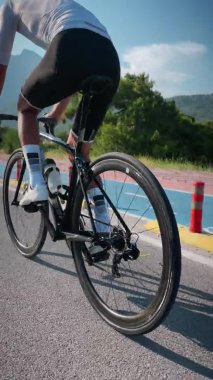 Bisiklet tekerleği ve kaset rotasyonu. Bisiklet teçhizatı ve sürüş rampası sistemini kapatın. Dikey video. Spor yarış bisikletine binen beyaz bisiklet ayakkabılı zayıf kaslı erkek bacakları. Bisiklet ve triatlon