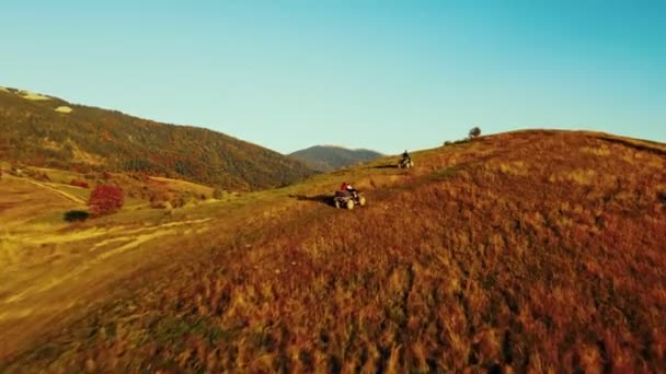 日没時にクアッドバイクを運転する人々 高い山道で4輪駆動車をスポーツ 夏には屋外の山の丘を探索する — ストック動画