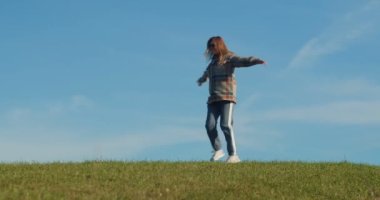 Güneşli bir günde, yeşil çimenlerde, dağ çayırında dans eden mutlu, gülen kadın. Çekici, alımlı, sıradan giyinen, gülümseyen, gülen ve güzel doğanın tadını çıkaran sarışın kadın. Sonbahar manzarası