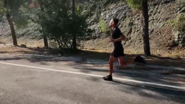 Hombre Corriendo Rápido Camino Asfalto Vacío Verdes Montañas Rocosas Atleta — Vídeos de Stock