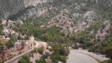 Dağ kanyonu, iki yeşil kayalık dağ ve dolambaçlı araba yolu arasında. Tepeleri ve nehri olan güzel bir dağ manzarası. Vahşi doğa manzarası