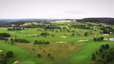 Golf sahasında golf delikleri ve küçük tepeler var. Golf sahasında yeşil çimlerle uçuyor.