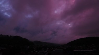 Büyük dağ zirvelerine doğru hızla ilerleyen dramatik pembe bulutların olduğu günden geceye geçiş. Pofuduk bulutlu dramatik mor gün batımı. Alacakaranlıkta güzel bulutlar