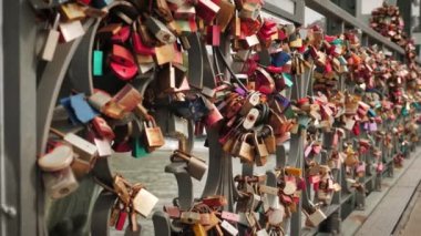 Iron locks of newlyweds hanging on bridge. Bridge of love. Tradition that perpetuates love. Wedding tradition. Little colored padlocks with names of bride and groom hang on tube of pedestrian bridge