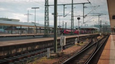 Red modern passenger train arriving to empty railway station. Train crossing empty railway platform. Transportation and logistics concept