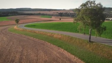 Boş asfalt yolda hızla bisiklet süren profesyonel bir bisikletçi. Bisikletli kadın triatlet eğitimi, yoğun dayanıklılık kardiyo çalışması. Bisiklet eğitimi. Spor motivasyonu. Fitness etkinliği