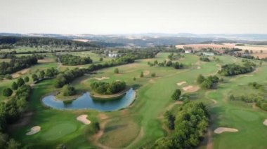 Golf sahası, hava manzarası. Küçük gölü ve yeşil ağaçlarıyla yeşil golf sahasının üzerinde uçuyor. Spor eğlencesi konsepti. Boş zaman aktivitesi. Doğa manzarası