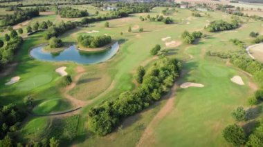 Golf sahası. Küçük gölü ve ağaçları olan yeşil golf sahası. Rahatlama zamanı, spor konsepti. Eğlence, eğlence aktivitesi. Golf sopası golf delikleri ve yeşil çimenli. Doğa manzarası