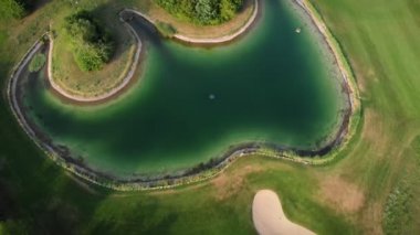 Sand bunker on golf field. Green lawn for play golf. Golf course with golf holes and small decorative lake. Golf field with pond. Leisure recreation activity. Sport concept. Summer holiday activity