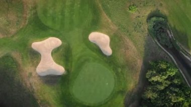 Golf field, aerial view. Flying over green lawn for play golf with golf holes and small pond. Green golf course with trees and hills. Summer recreation activity. Leisure activity. Nature landscape