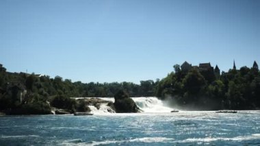 Rheinfall waterfall on Rhine river in Switzerland with massive water power. The largest waterfall in Switzerland and Europe. Waterfall with huge massive stream of water falling into river, timelapse